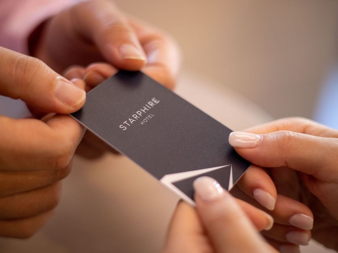 Two hands exchanging a black guest card for Starphire Hotel.