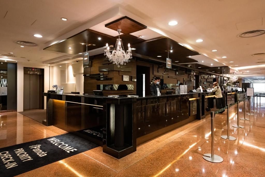 Hotel lobby with polished floors and a chandelier, featuring a reception desk with staff attending to guests.